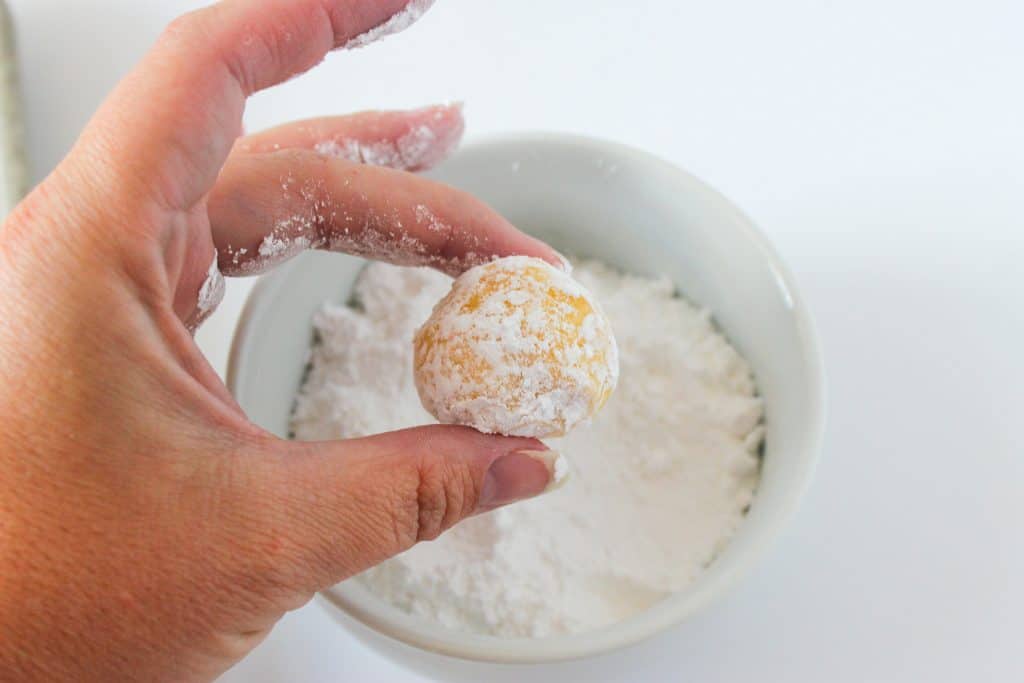 hand holding gooey butter cake cookie dough ball after dipping it in powdered sugar