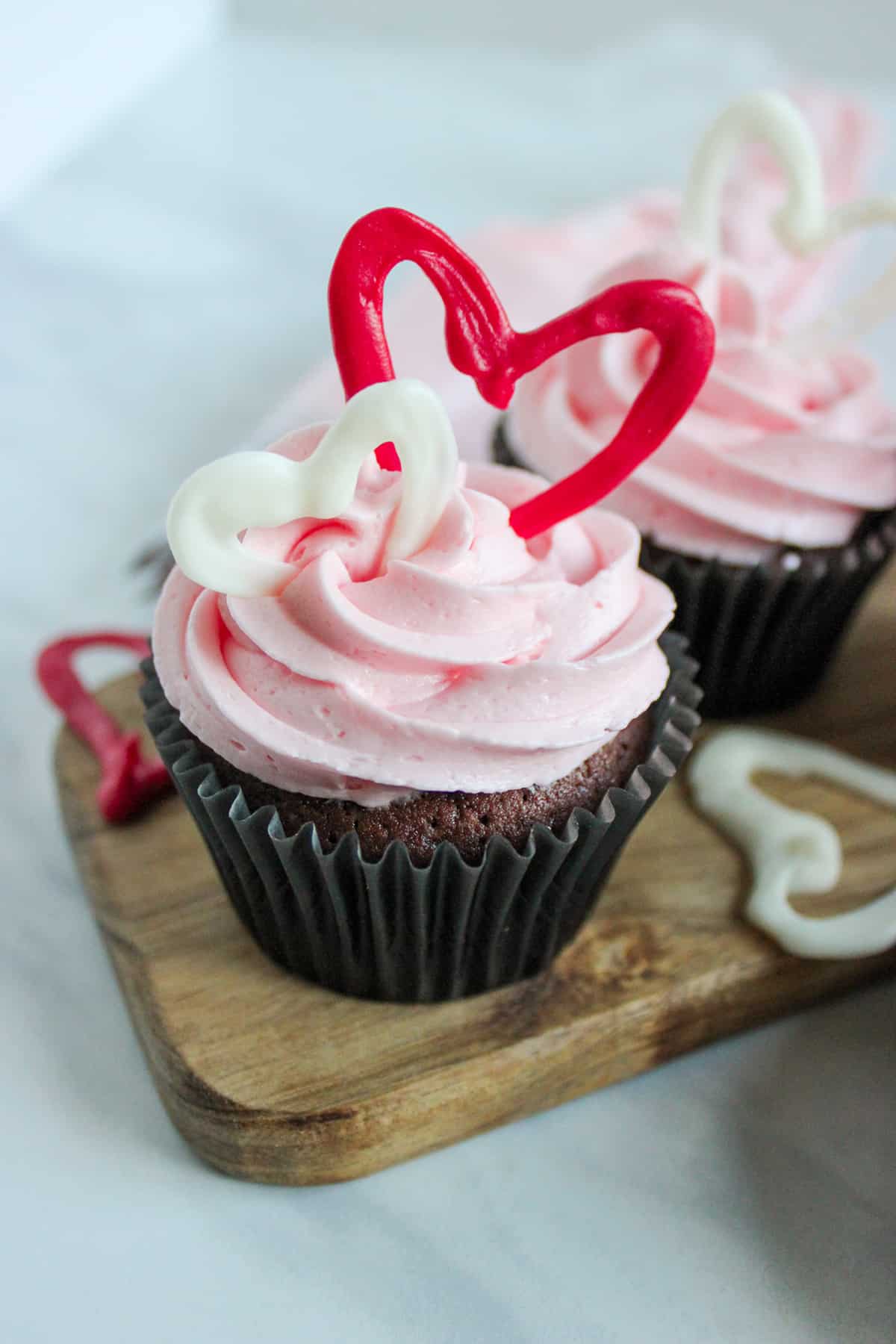 chocolate cupcakes with pink buttercream frosting and red chocolate hearts