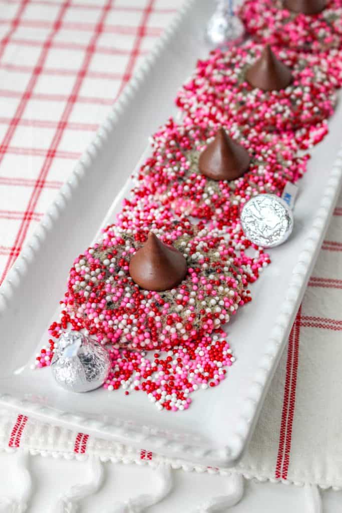 cookies and cream blossom cookies with hershey's kisses on a white plate with red and pink sprinkles