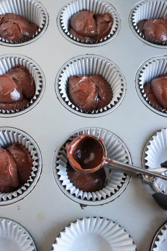 chocolate cupcake batter being scooped into cupcake tin