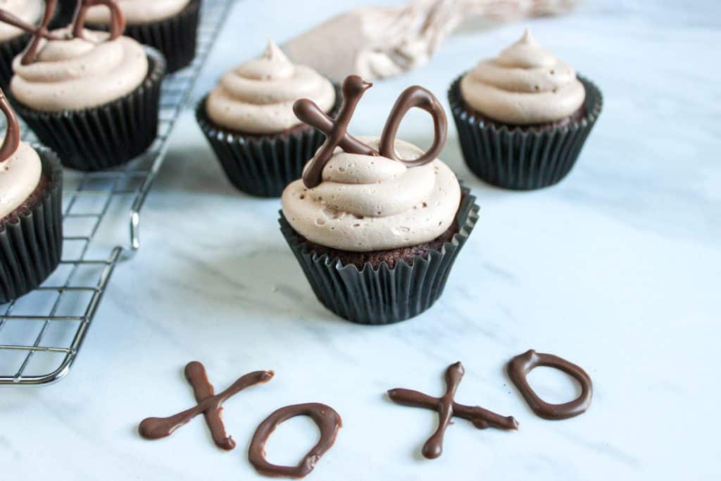chocolate cupcakes with nutella buttercream frosting on marble counter with chocolate "xo xo" decoration