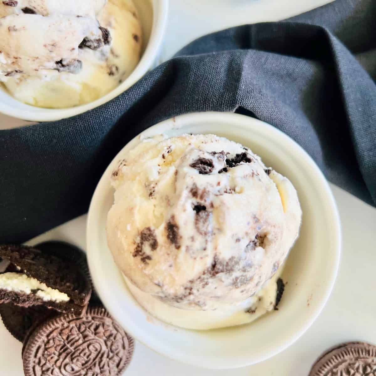 Oreo Cookies Cream Ice Cream Overhead ramekins filled with scoops next to black linen napkin and sandwich cookies