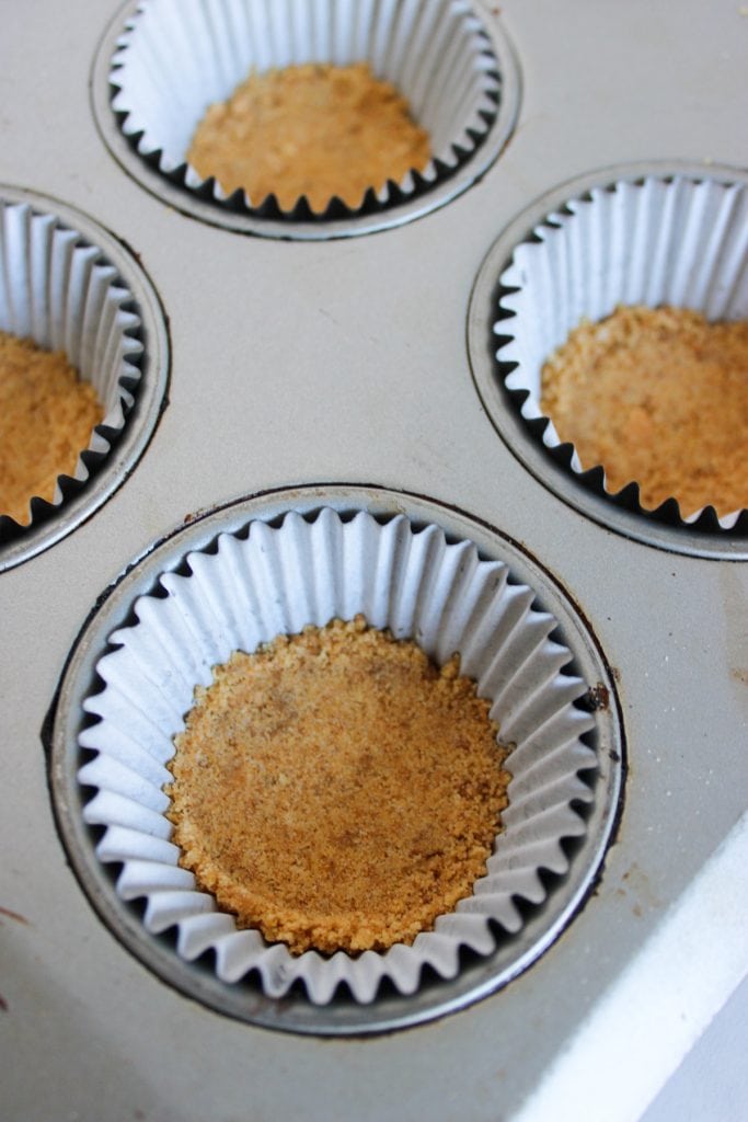 graham cracker mixture in lined cupcake tin