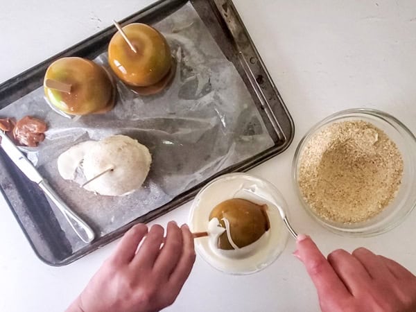 dipping the caramel apples into the white chocolate layer