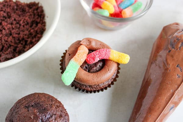 cupcake with circle of frosting and gummy worms on top