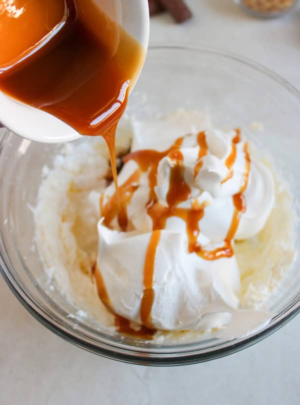 adding caramel sauce to bowl of cream cheese and cool whip