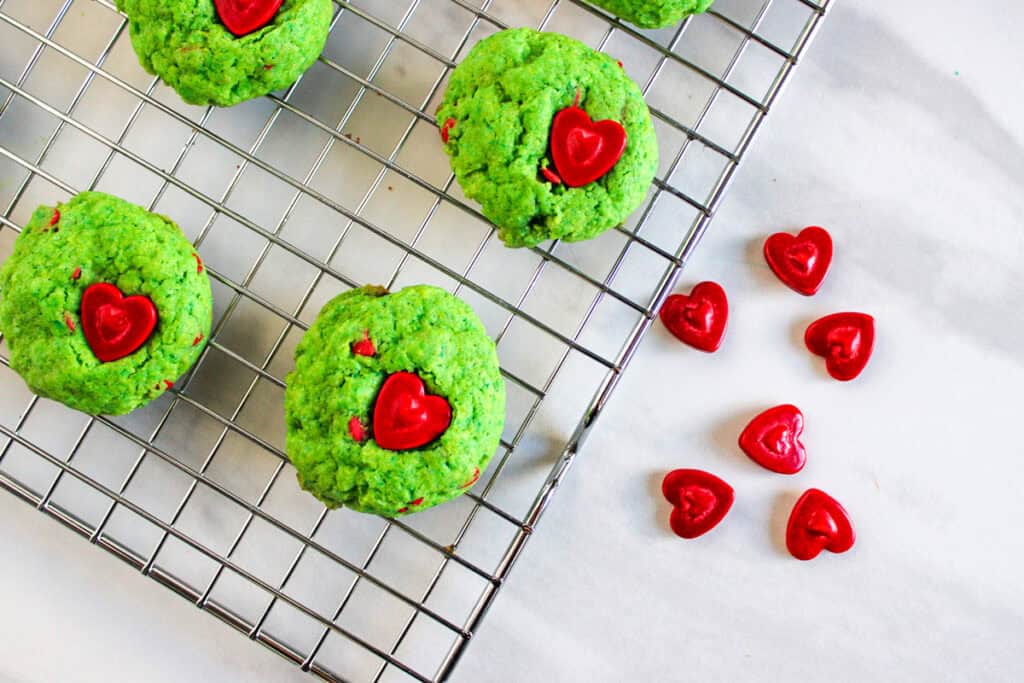 placing large red candy hearts into freshly baked cookies