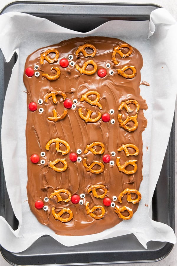 pretzels, candy eyes, and red m&ms pressed into the melted chocolate to look like reindeer faces