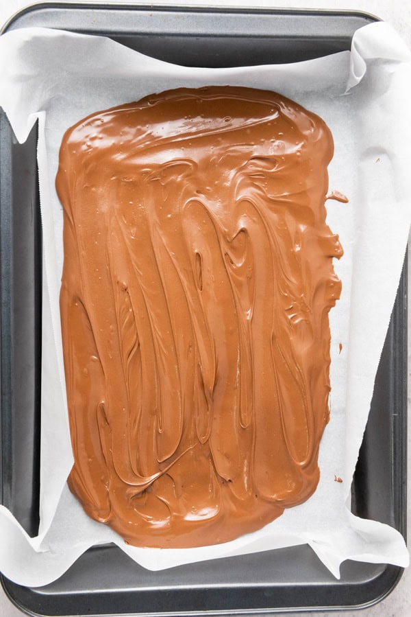 melted chocolate spread over parchment paper-lined baking pan