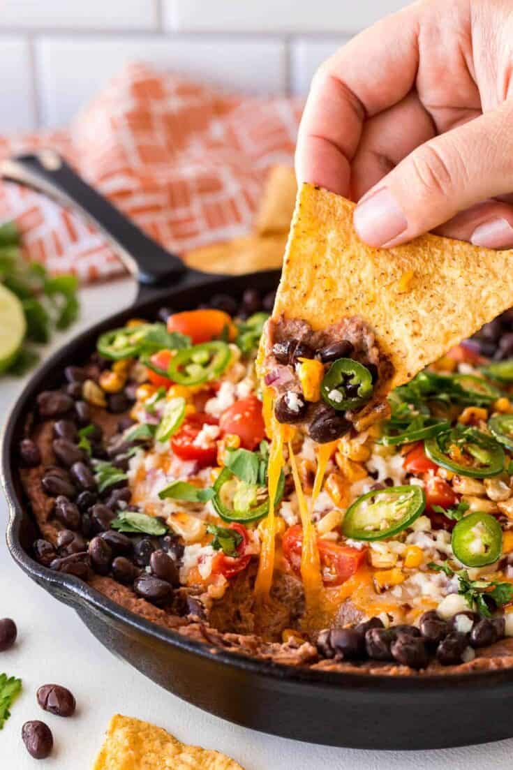 Warm Rustic Black Bean Dip dipping in a bean dip 16