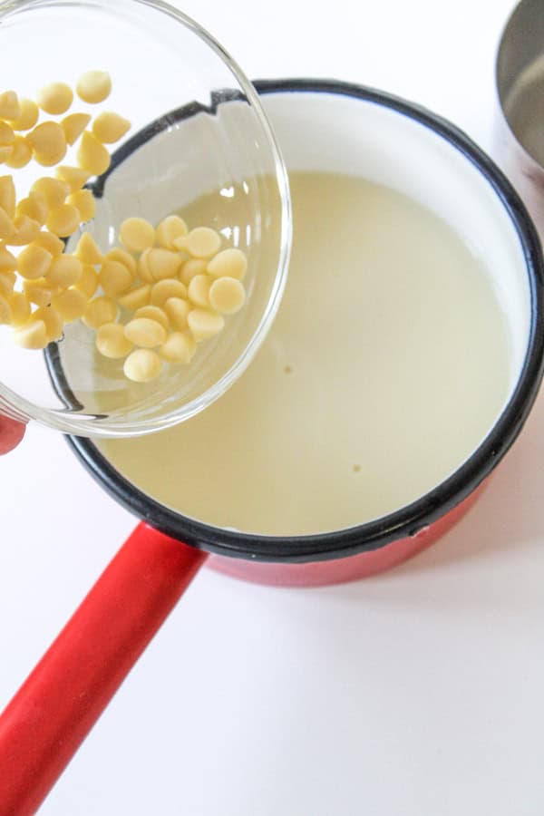 adding white chocolate chips to the milk and sugar mixture