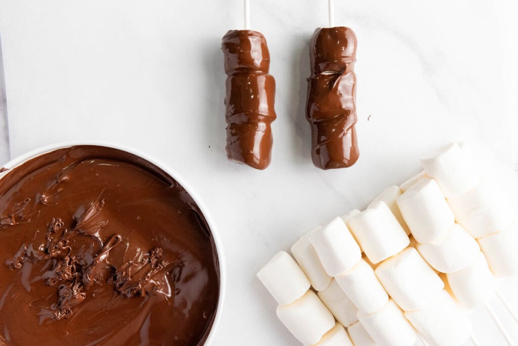 dipping the marshmallows into melted chocolate