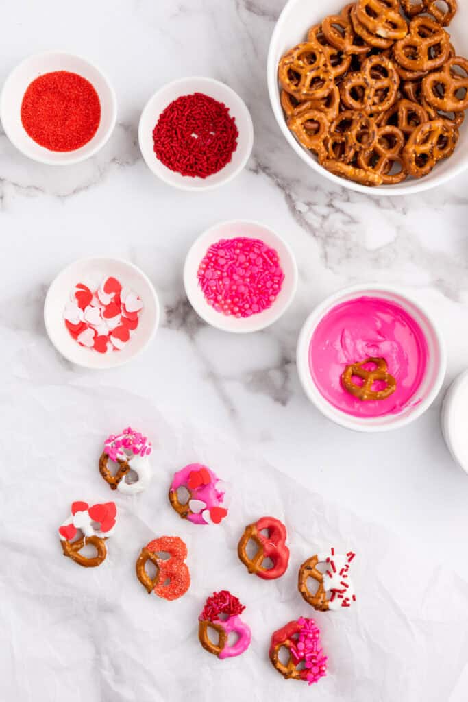 adding sprinkles to the candy coated pretzels