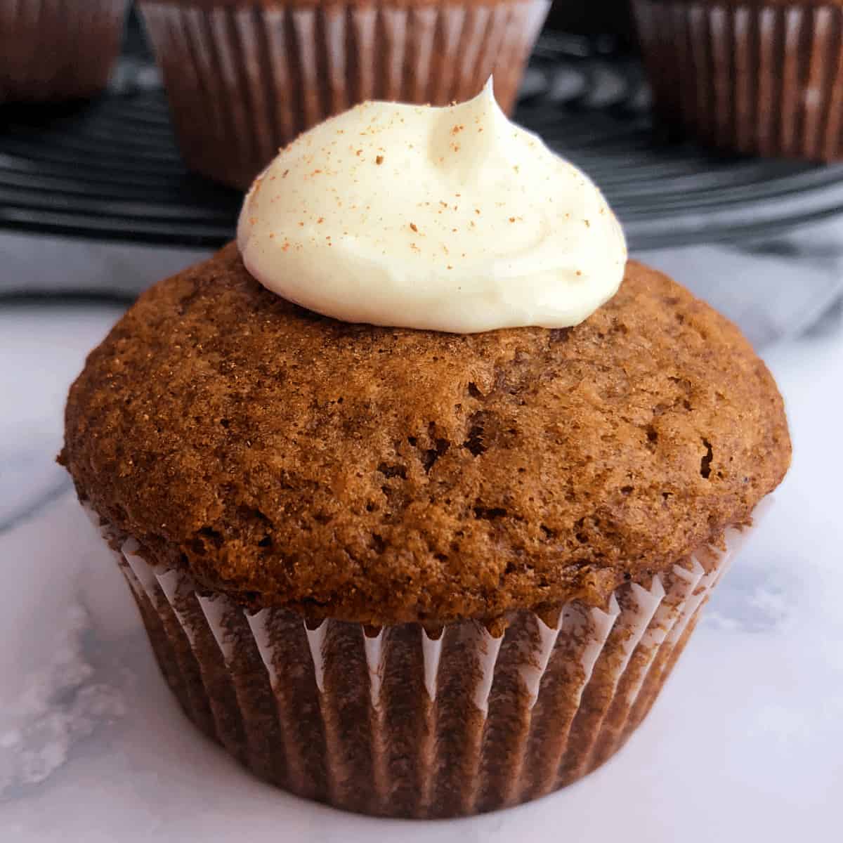 banana muffin with cream cheese frosting and ground cinnamon