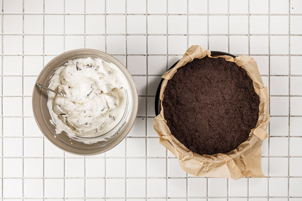 left: oreo cheesecake filling in a bowl; right: oreo crust in lined pan