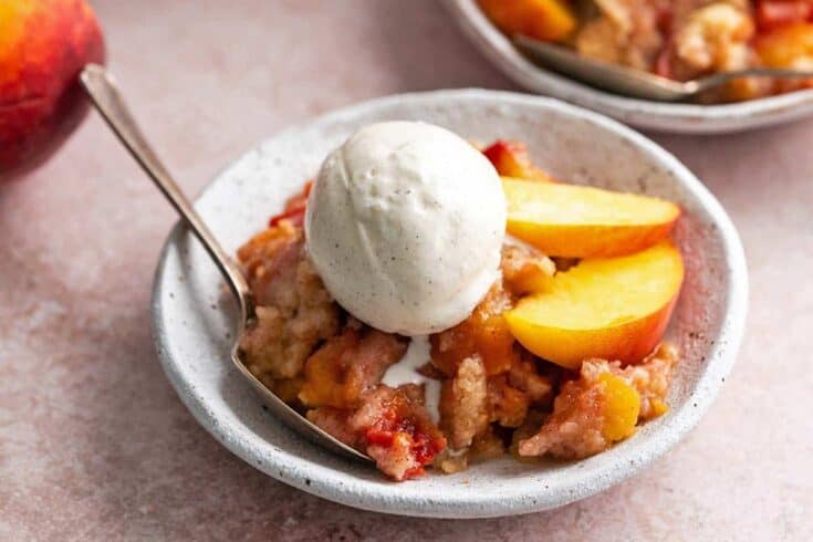 warm peach cobbler cake with ice cream melting on top