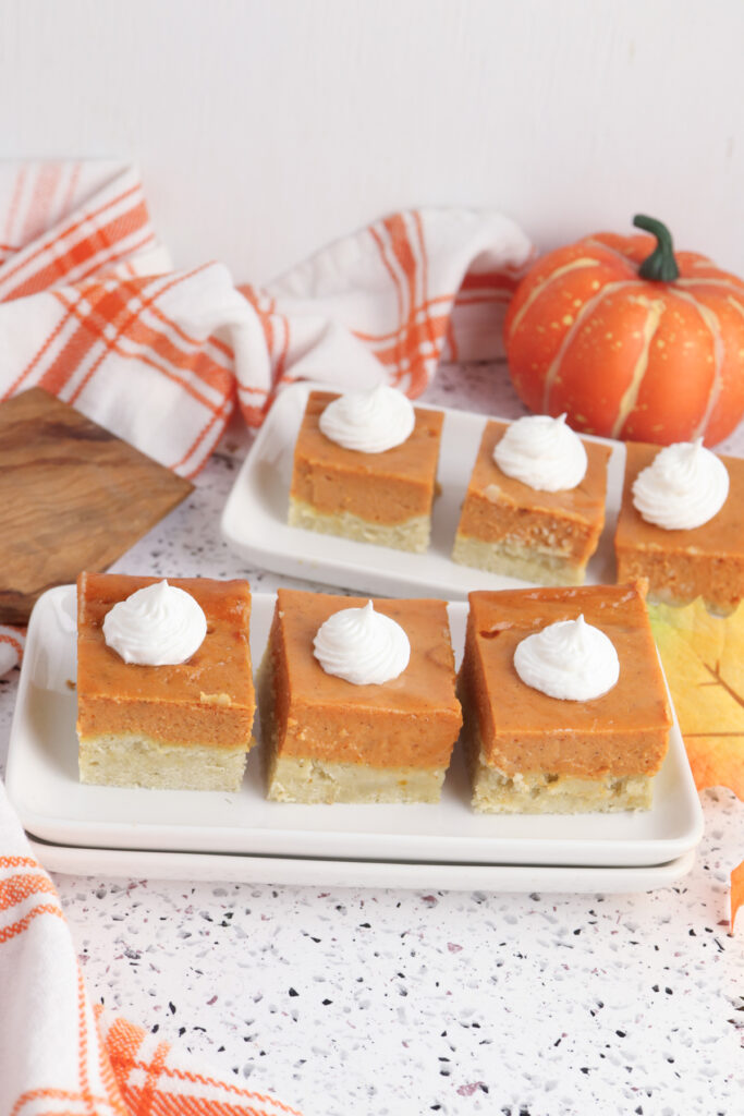 finished pumpkin pie bars on a plate, topped with whipped cream