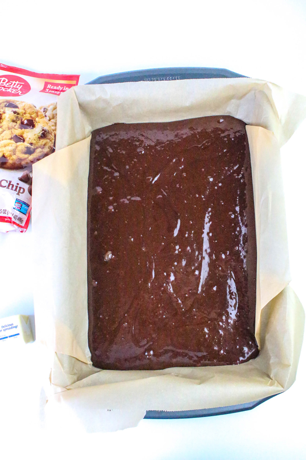 brownie batter in bottom of parchment lined pan