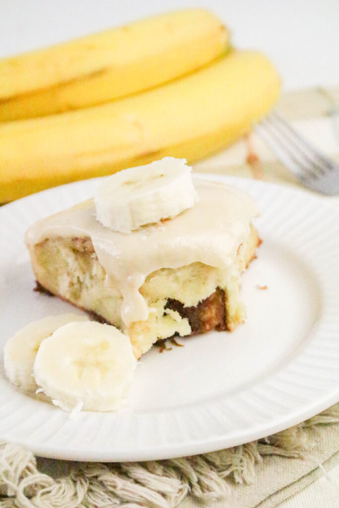 banana cinnamon roll with maple cream cheese icing on a plate
