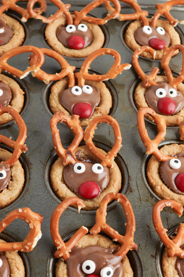 press candies and pretzels into the peanut butter cups while they are slightly warm