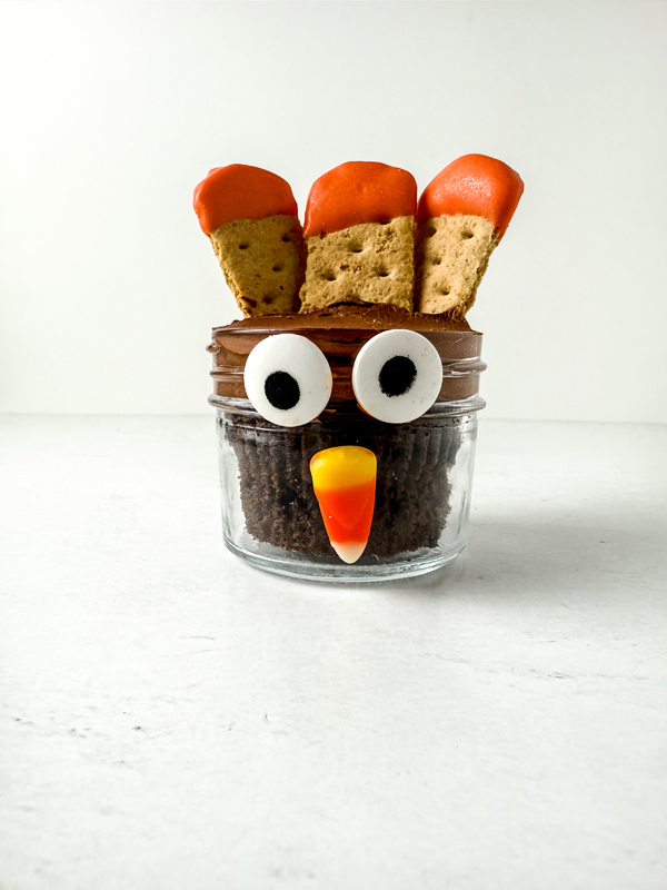 add the eyes and candy corn to the outside of the jars to make turkey faces
