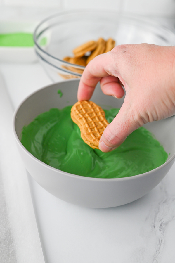 dip one side of each nutter butter cookie into the green candy