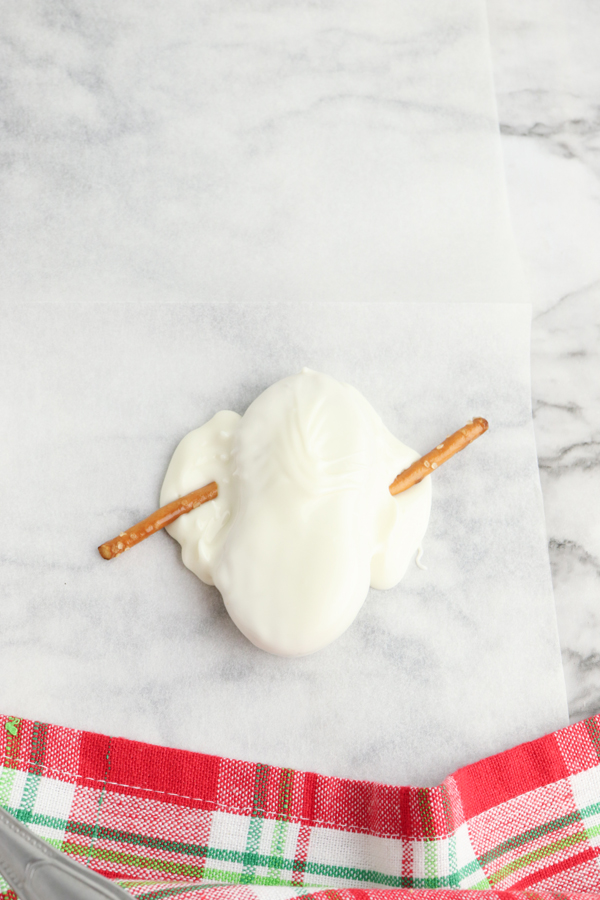 swirl melted candy around the cookie to make it look like melted snow and add pretzel arms