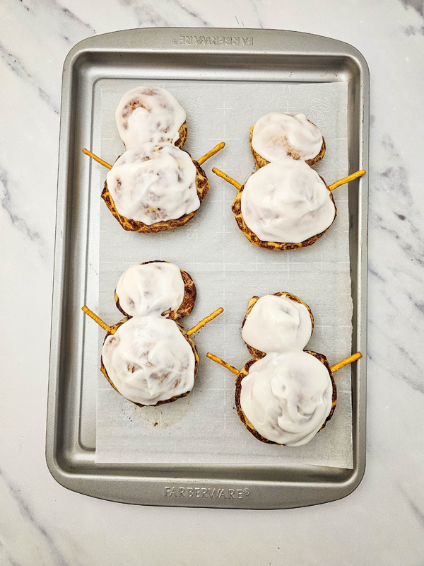 ice the cinnamon rolls and apply pretzel arms