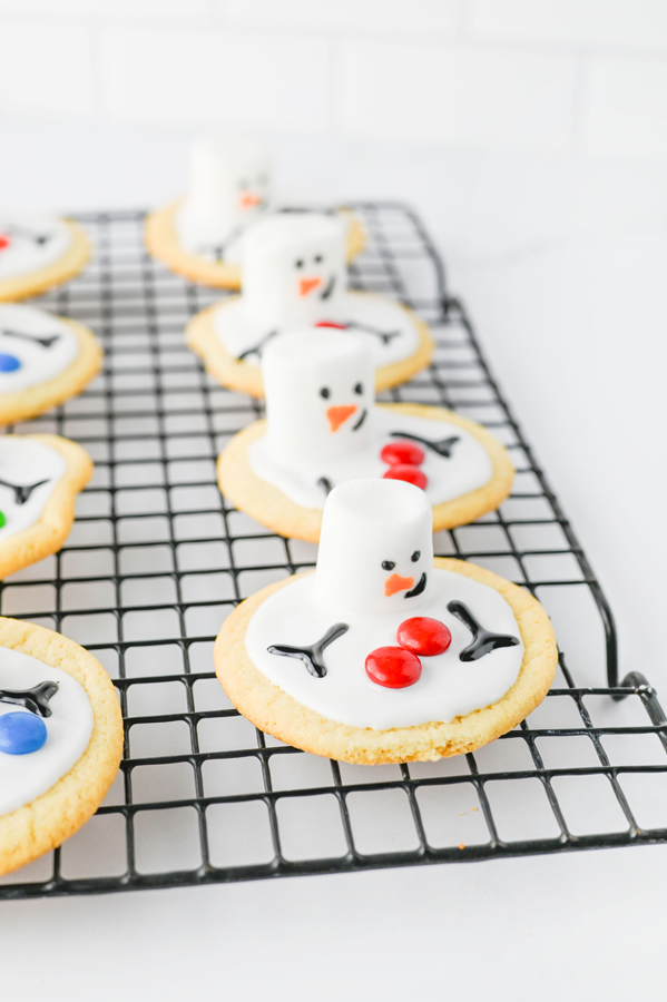 use the black and orange icing to make snowman faces and arms on each cookie