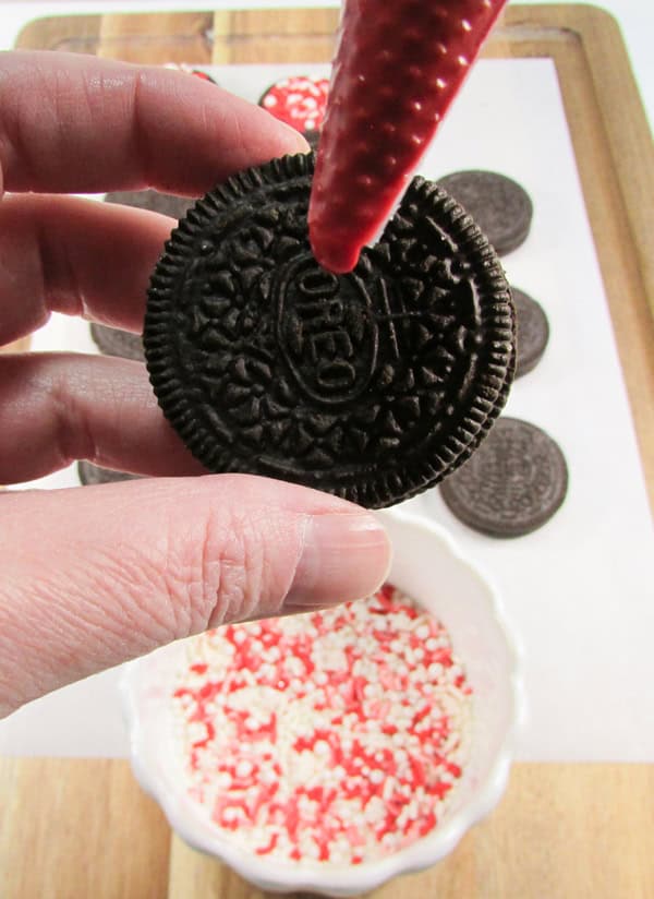 pipe the red candy onto the center of the oreo cookie