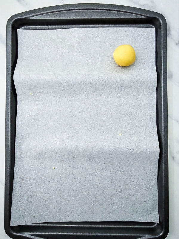 dough ball on parchment lined cookie sheet